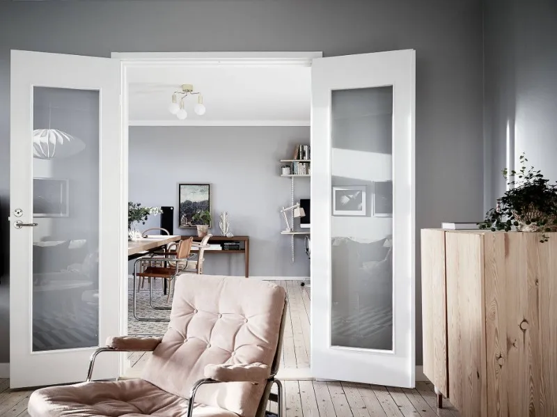 Scandinavian apartment interior with lounge chair, dining furniture and light wood storage cabinet